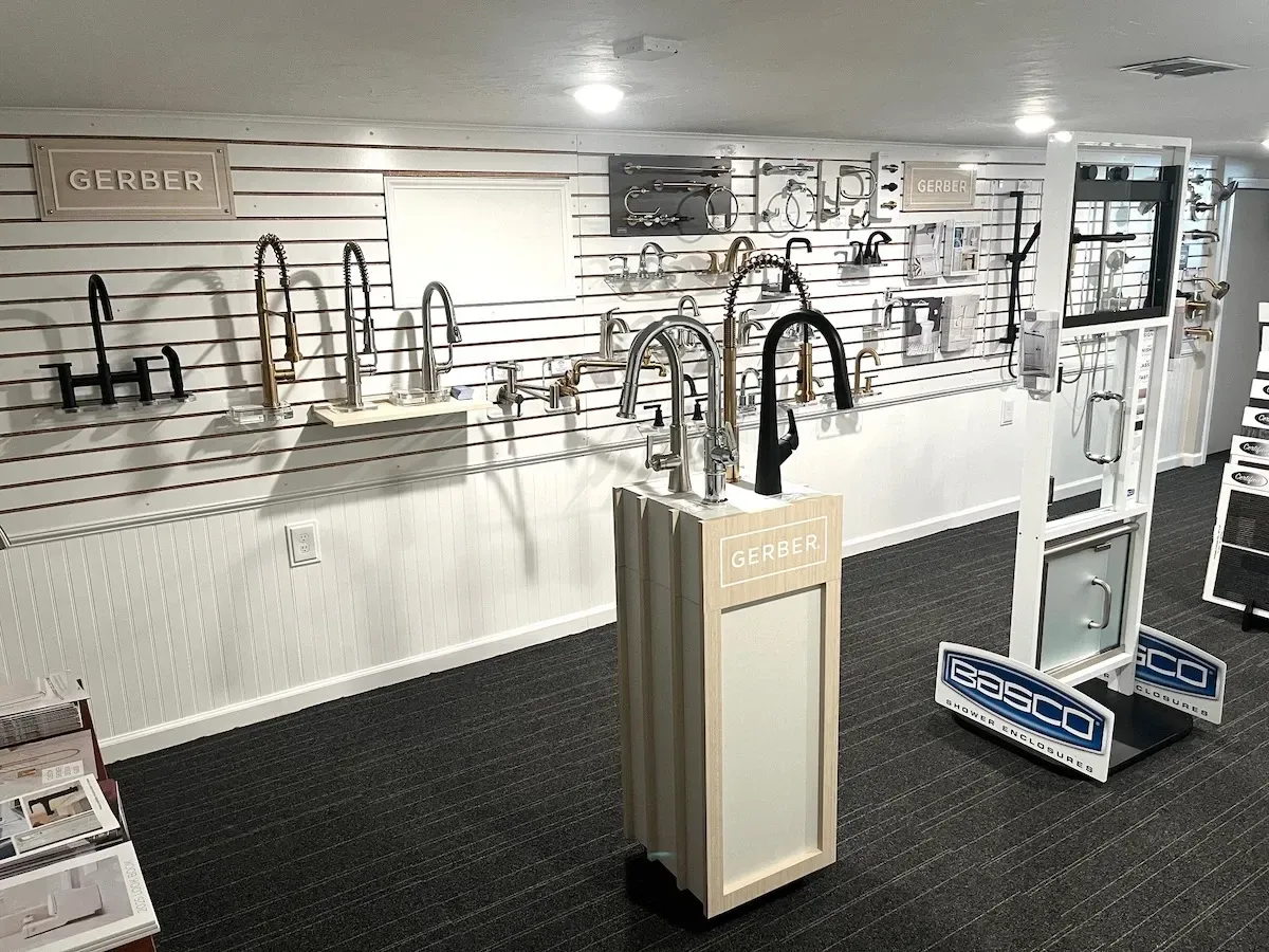 Plumbing showroom with sinks, faucets, and shower fixtures displayed on wall-mounted racks.