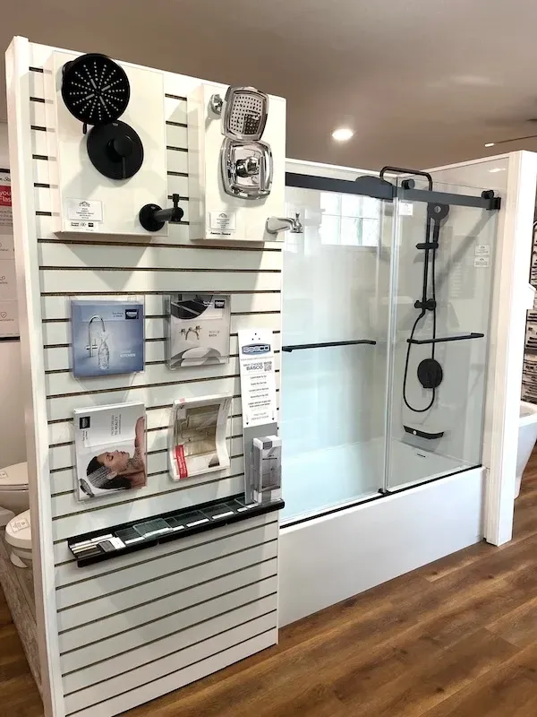 Shower display in a home improvement showroom with wall-mounted fixtures and a glass shower enclosure.