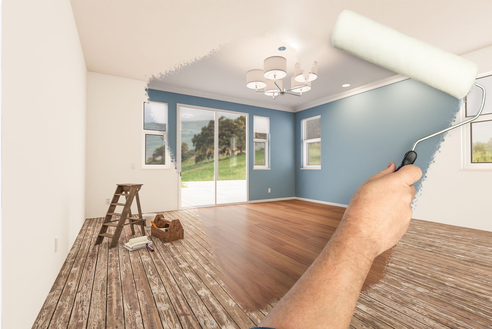 Person painting a blue-walled room with wood floors and patio doors, using a paint roller.