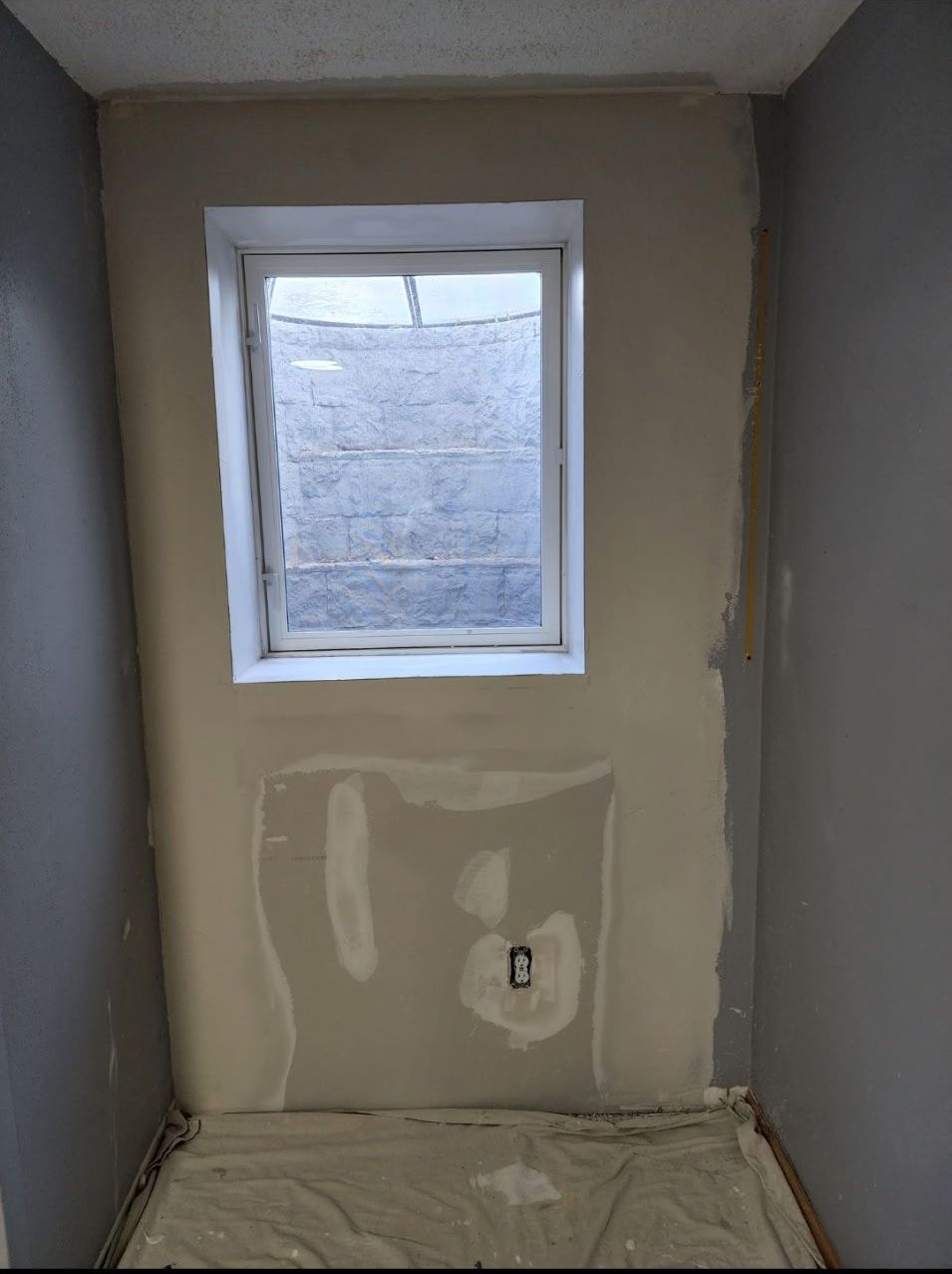 An empty room with a window and a white sheet on the floor
