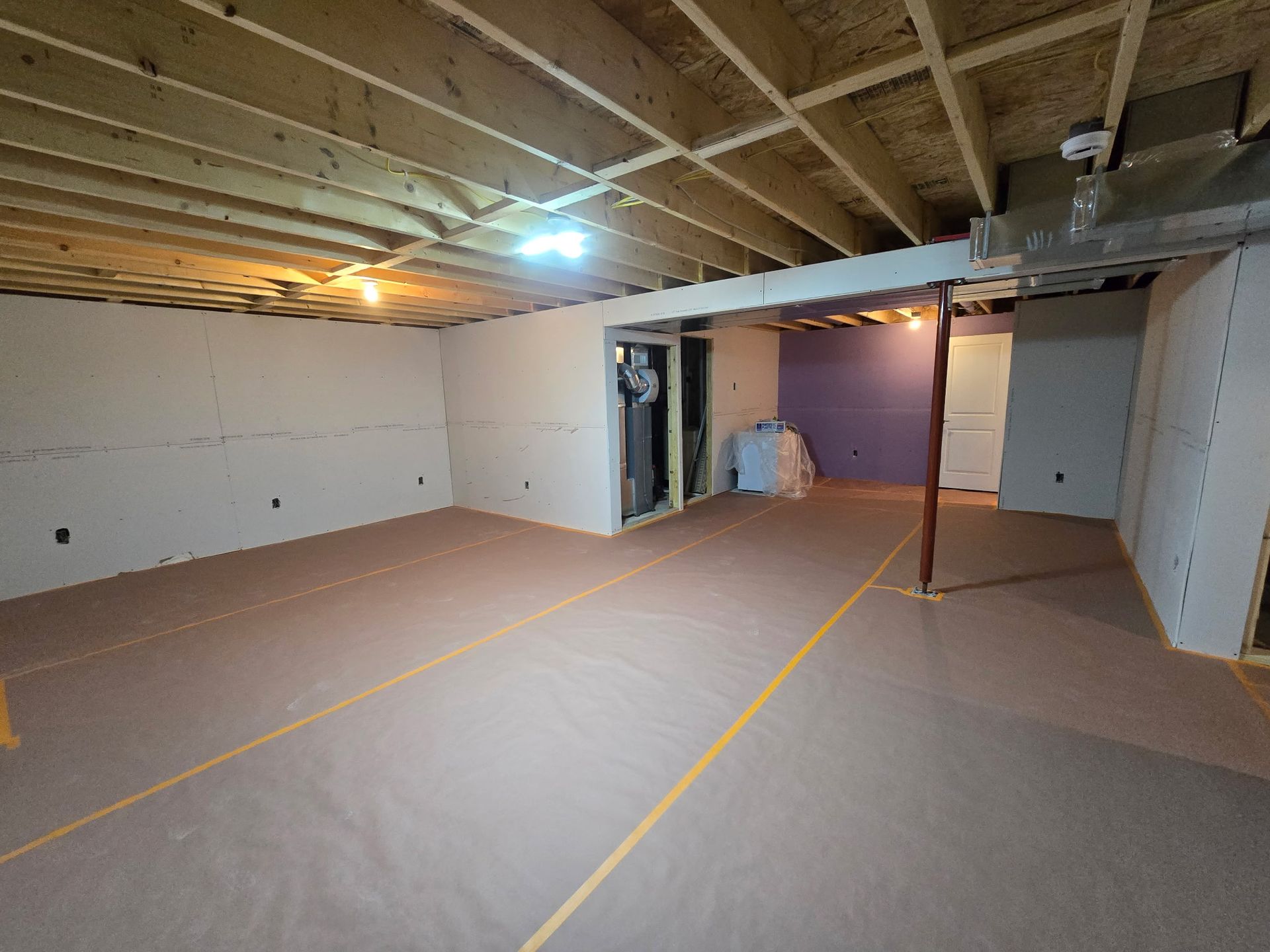 An empty basement with a wooden ceiling and a purple wall.