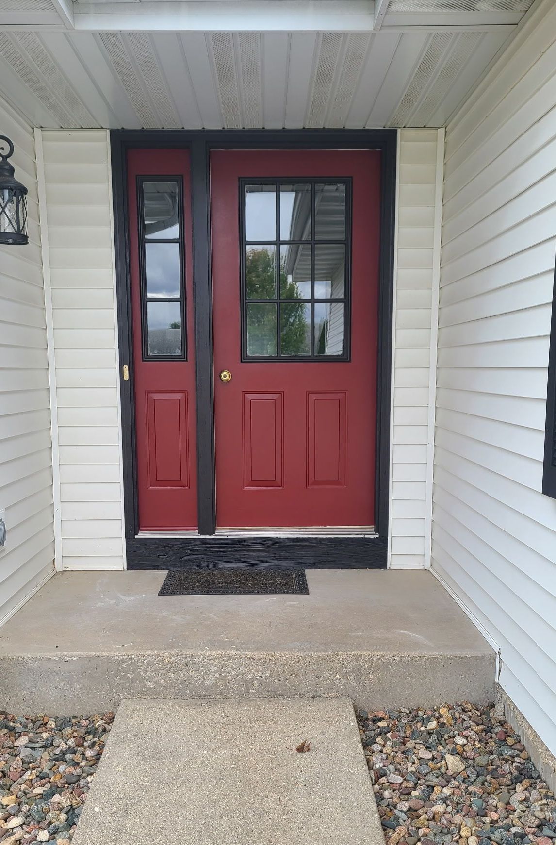 A red door with black trim is on a white house.