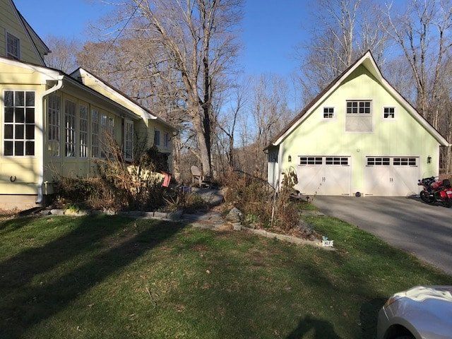 Suburban driveway with two pale yellow houses, leafless trees, and a green lawn on a sunny day