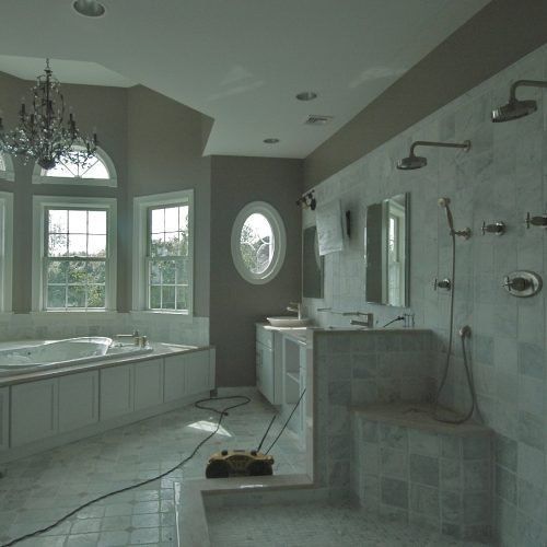 Luxury bathroom with a tub, tiled walk-in shower, and large windows letting in soft daylight.