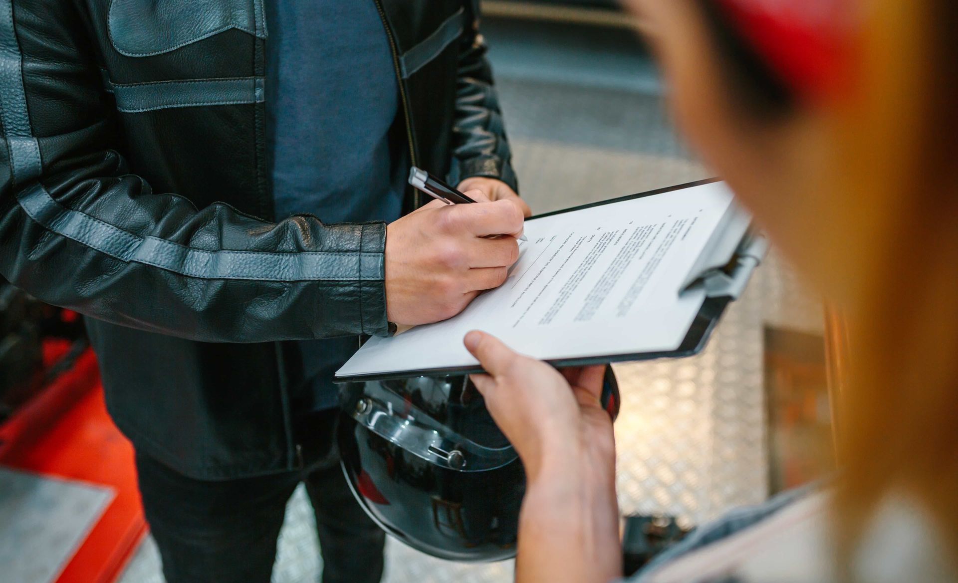 Person holding a clipboard while another signs a form outdoors.