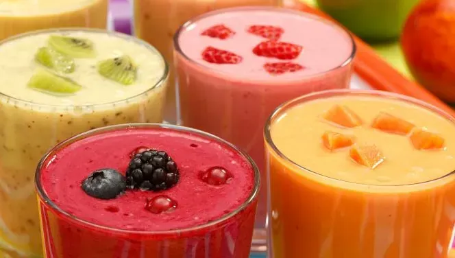 Pink, red, yellow, and orange cannabis infused fruit smoothies and drinks are filled to the rim of 4 glasses.