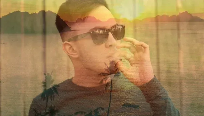 A young man in black sunglasses tokes on a joint with a golden tropical sunset overlay.