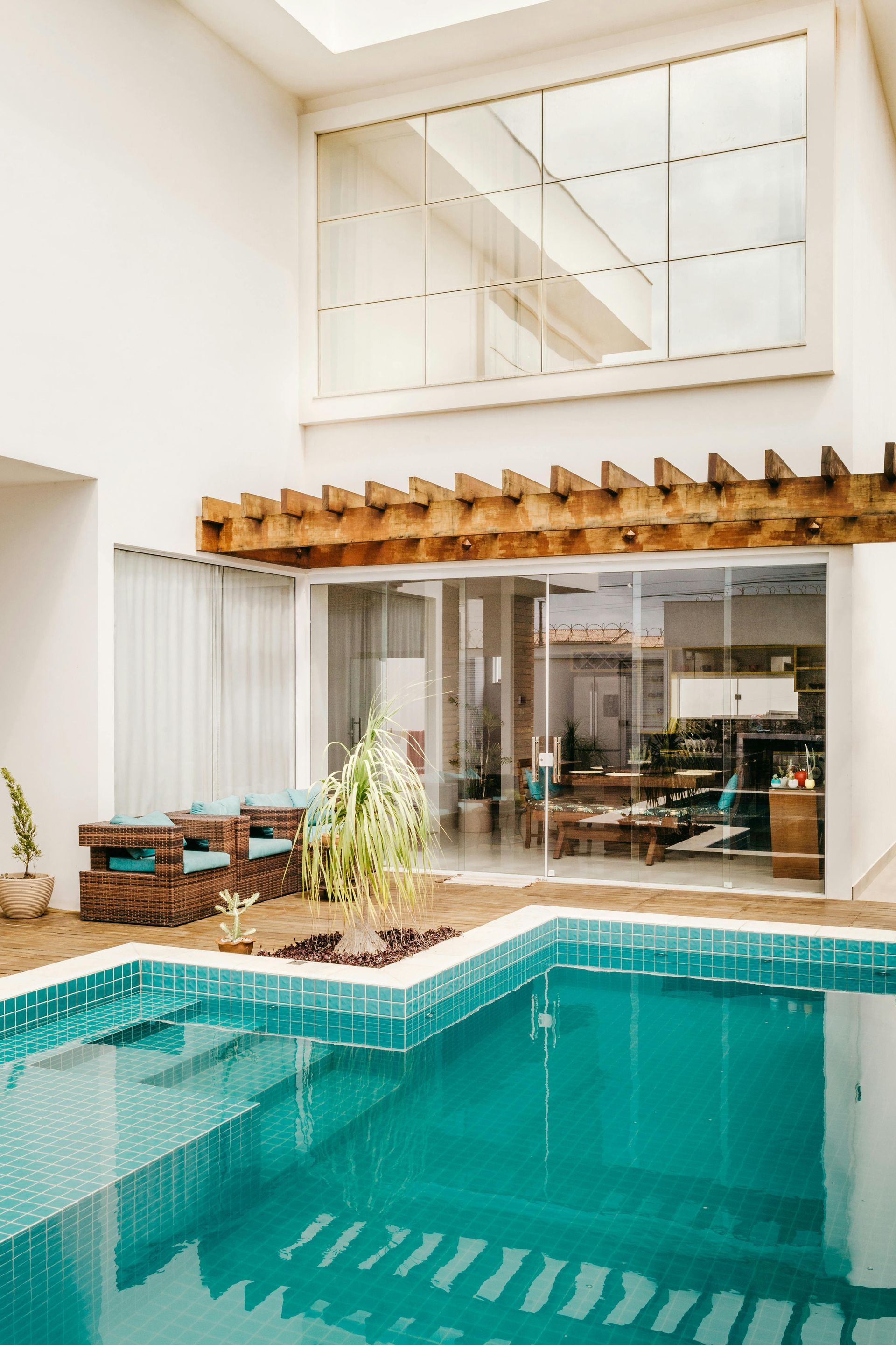 L-shaped custom pool set in a brick deck with a wood pergola
