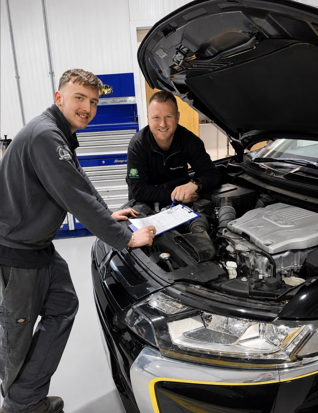 Mechanic in gray coveralls working beside a large truck inside a garage