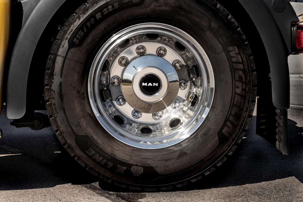 Close-up of a truck wheel and tire with a chrome hubcap on pavement.