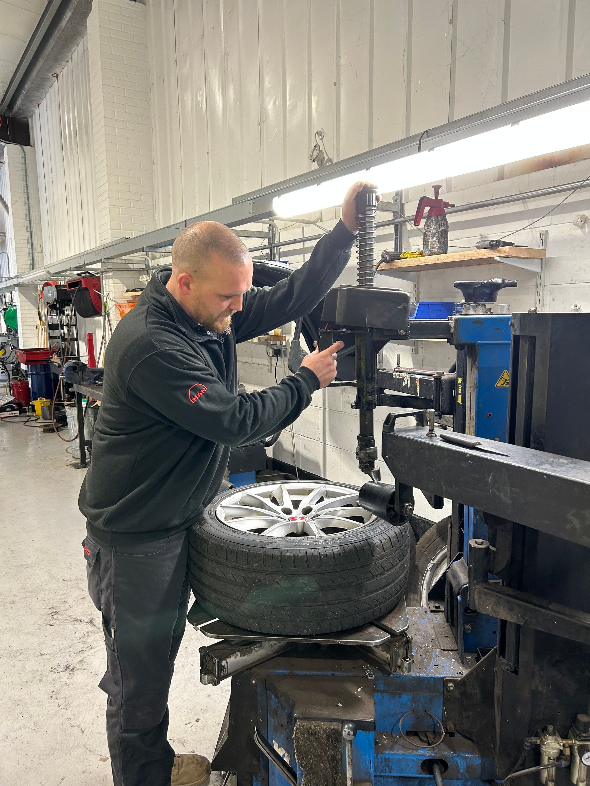 Mechanic using a tire machine to change a wheel in a garage