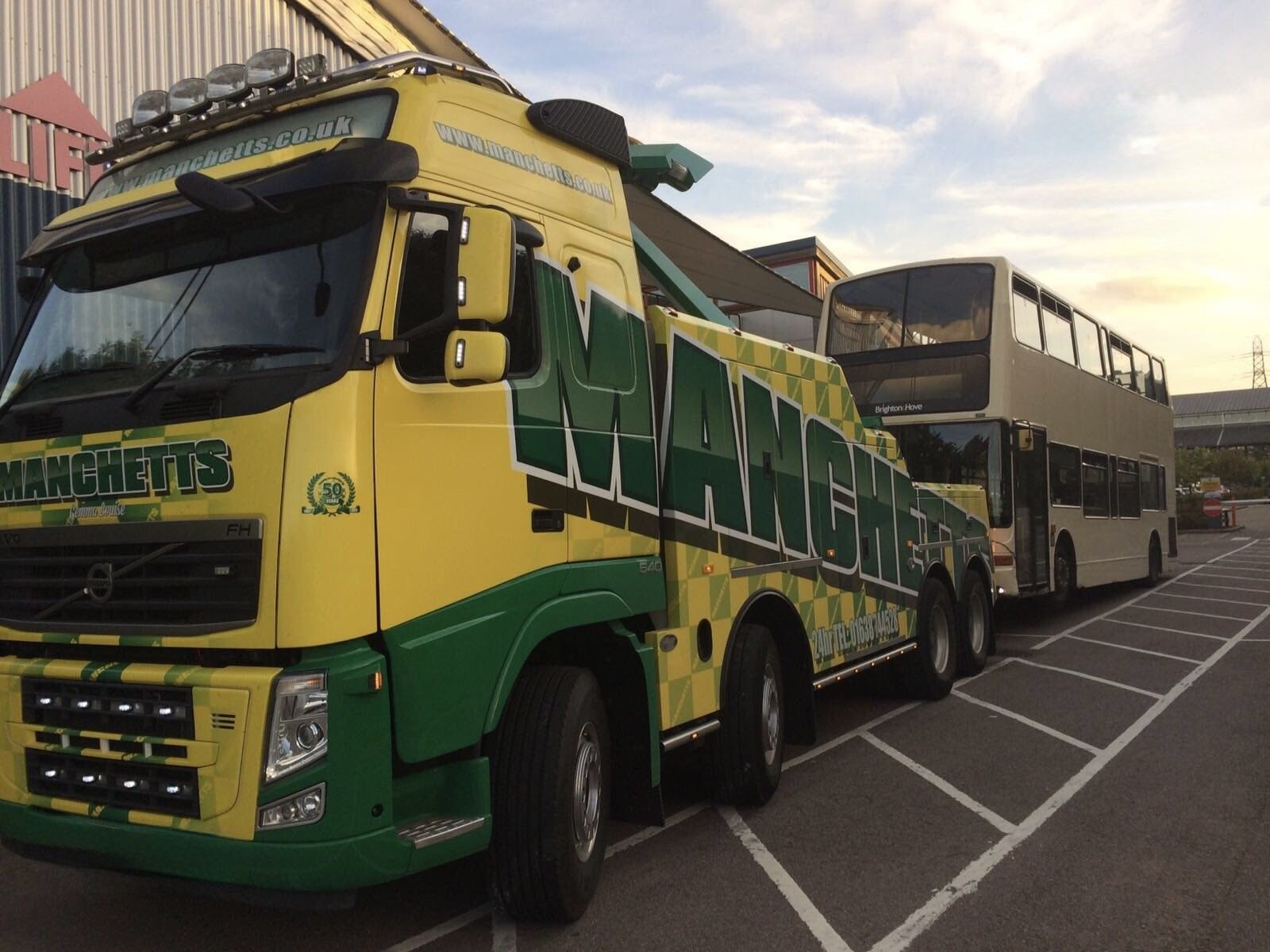 Double-decker bus being recovered by Green and yellow Manchetts tow truck
