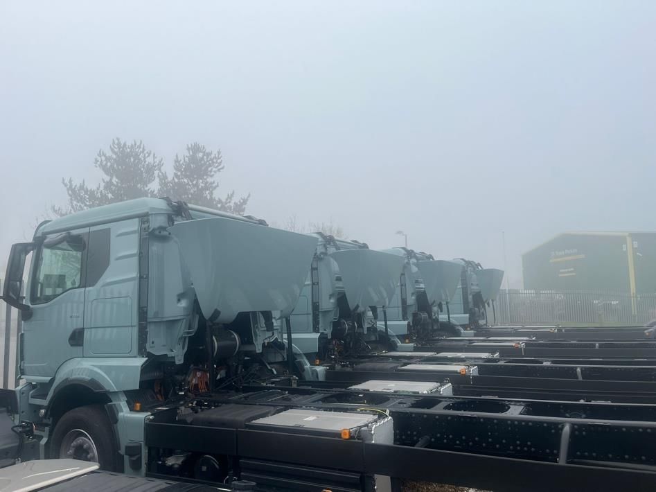 Row of gray semi-trucks parked in a foggy lot