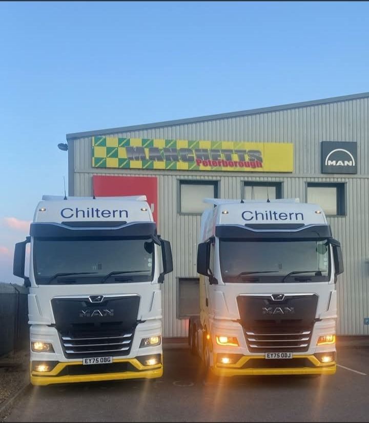 Two Chiltern trucks parked side by side outside a warehouse at dusk