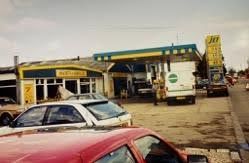 Gas station forecourt with cars parked beside a small service station and JET fuel sign