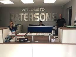 Reception desk with three people under a “Welcome to Patersons” wall sign.