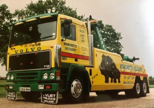 Yellow and black Manchetts Volvo F12 recovery truck on a roadside, with wildlife rescue graphics on the side.