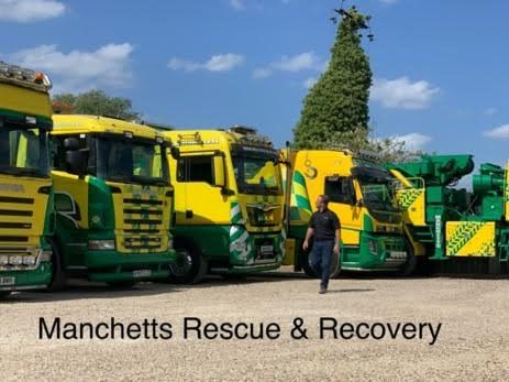 Yellow and green Manchetts rescue trucks parked outdoors with a person walking in front, labeled “Manchetts Rescue & Recovery”