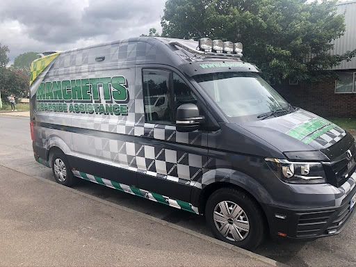 Black and gray Manchetts service van with green lettering parked on a wet street