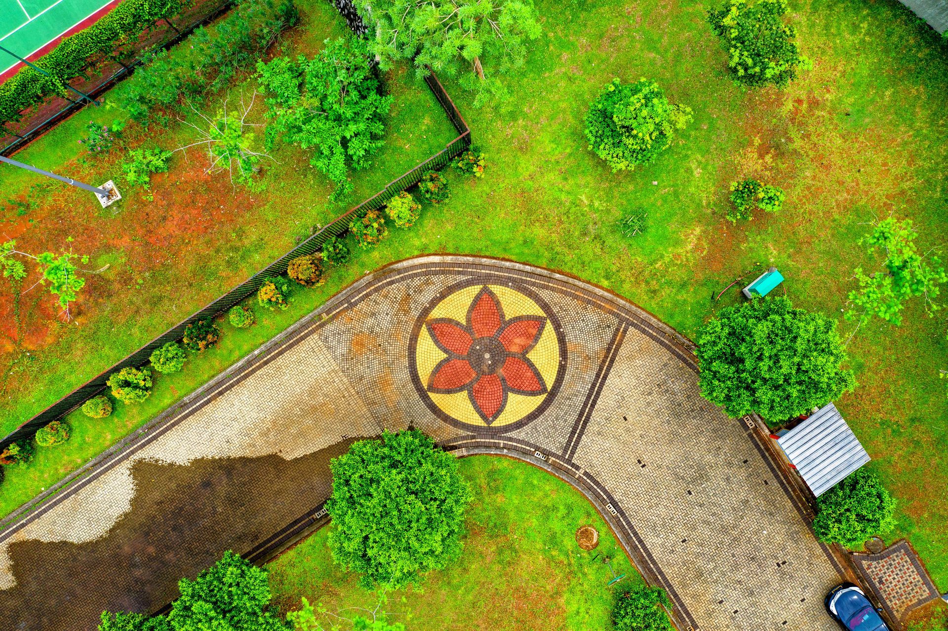 An aerial view of a park with a flower design on the sidewalk.