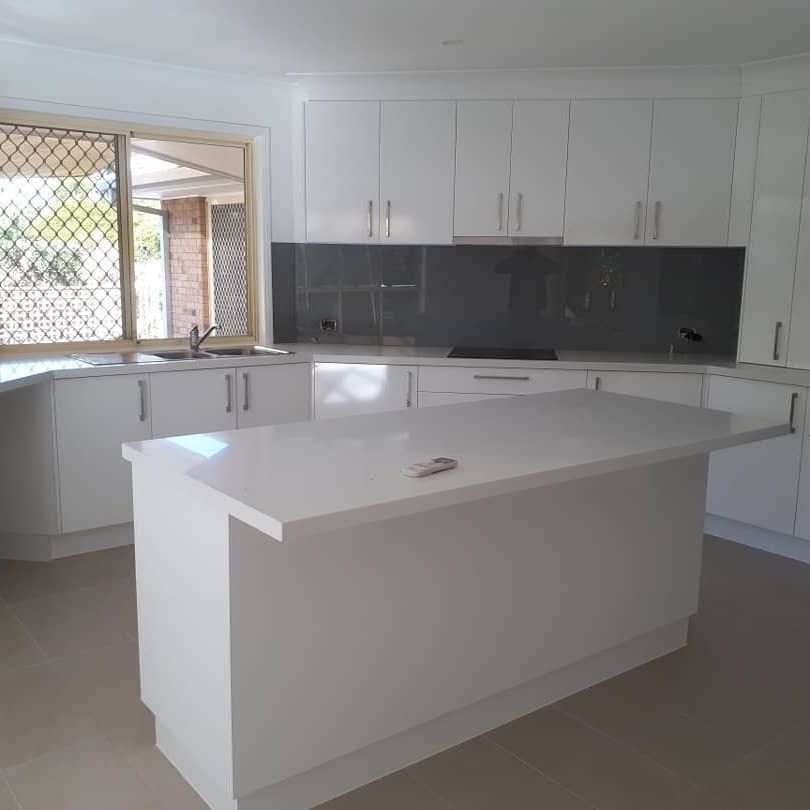 A Kitchen With White Cabinets And A Large Island — Pottsville Carpentry and Home Maintenance In Pottsville, NSW