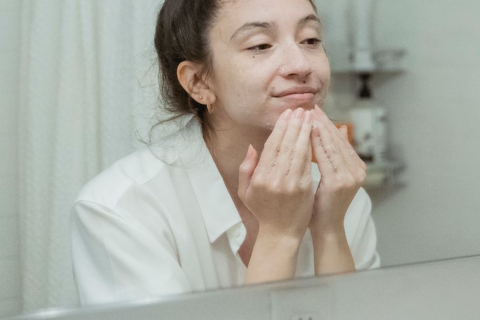 Woman examining dull skin in the mirror before radiance treatment in Seoul