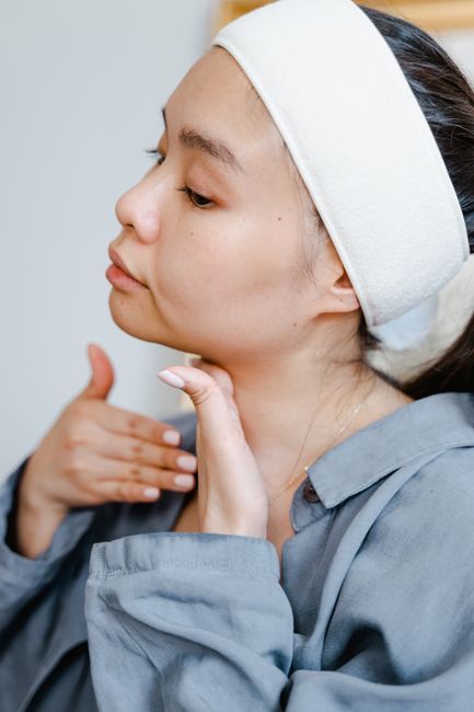 Woman applying skincare to neck lines before treatment in Seoul