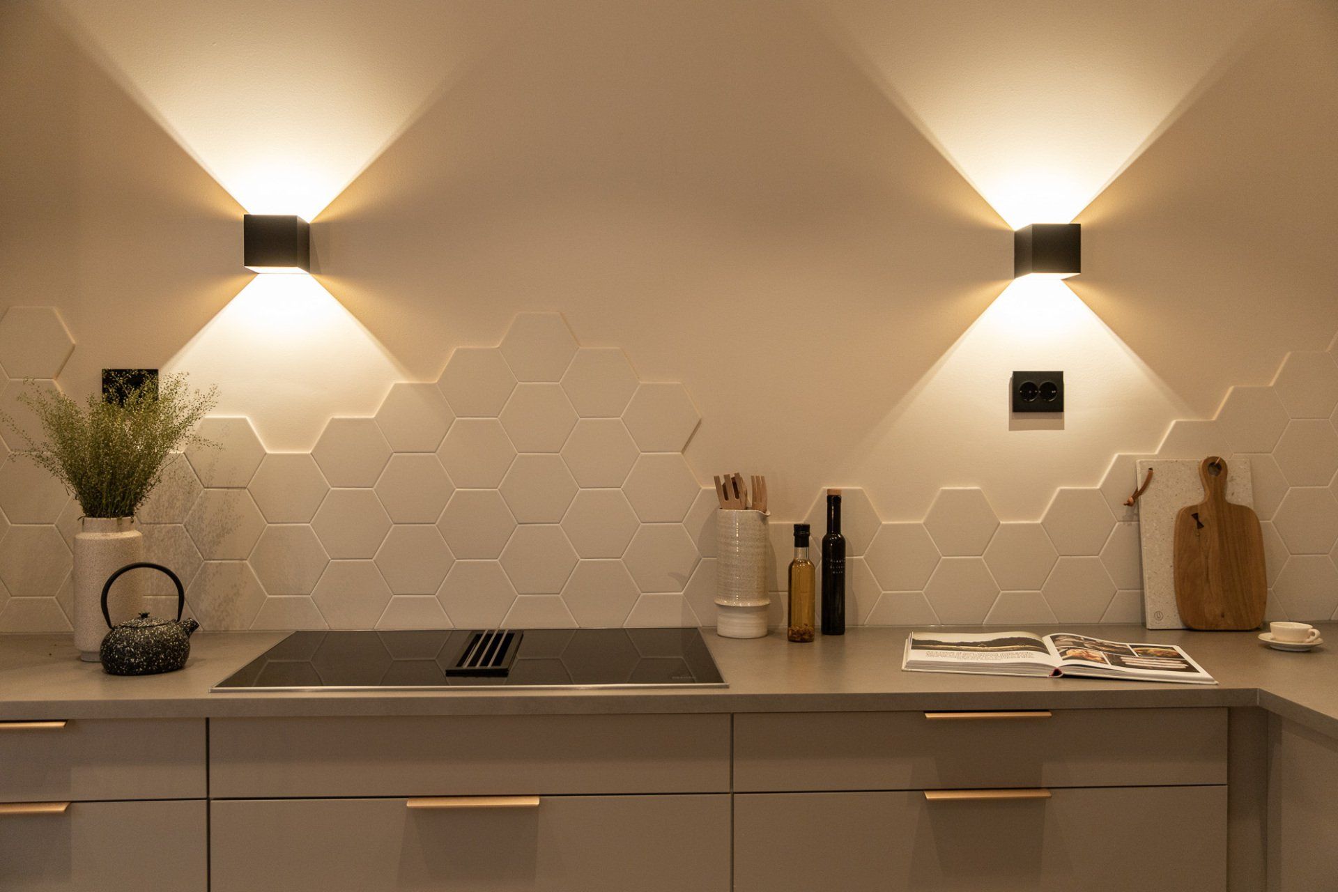 Moderne kjøkken med beige skap, sekskantflisede bakplater, lys under skap og benkeplatedekor