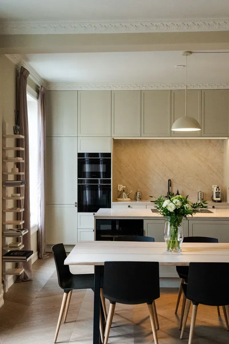 Moderne kjøkken-spisestue med beige skap, svarte stoler og et hvitt bord ved et vindu