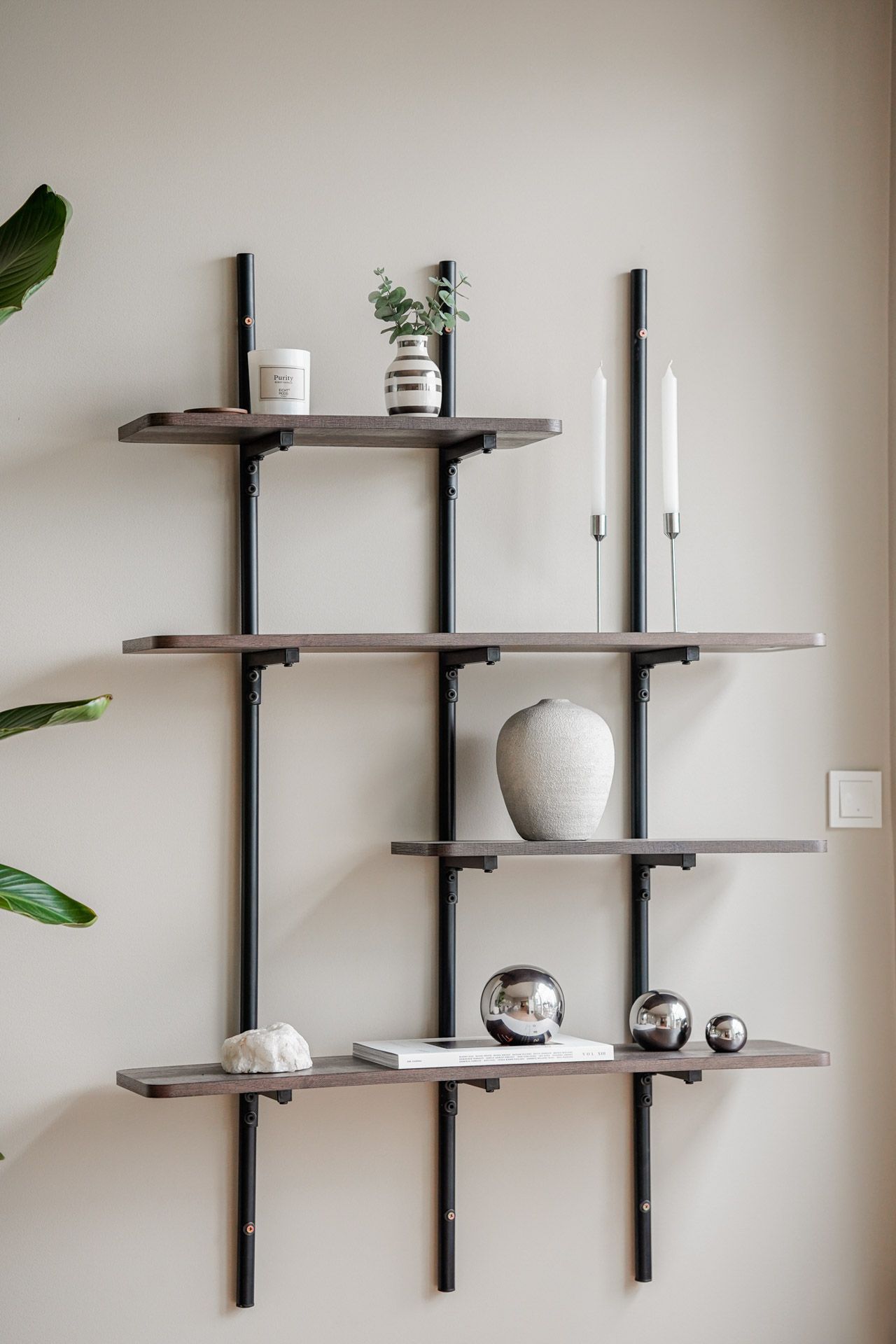 Minimalistiske veggmonterte hyller med dekor mot en beige vegg