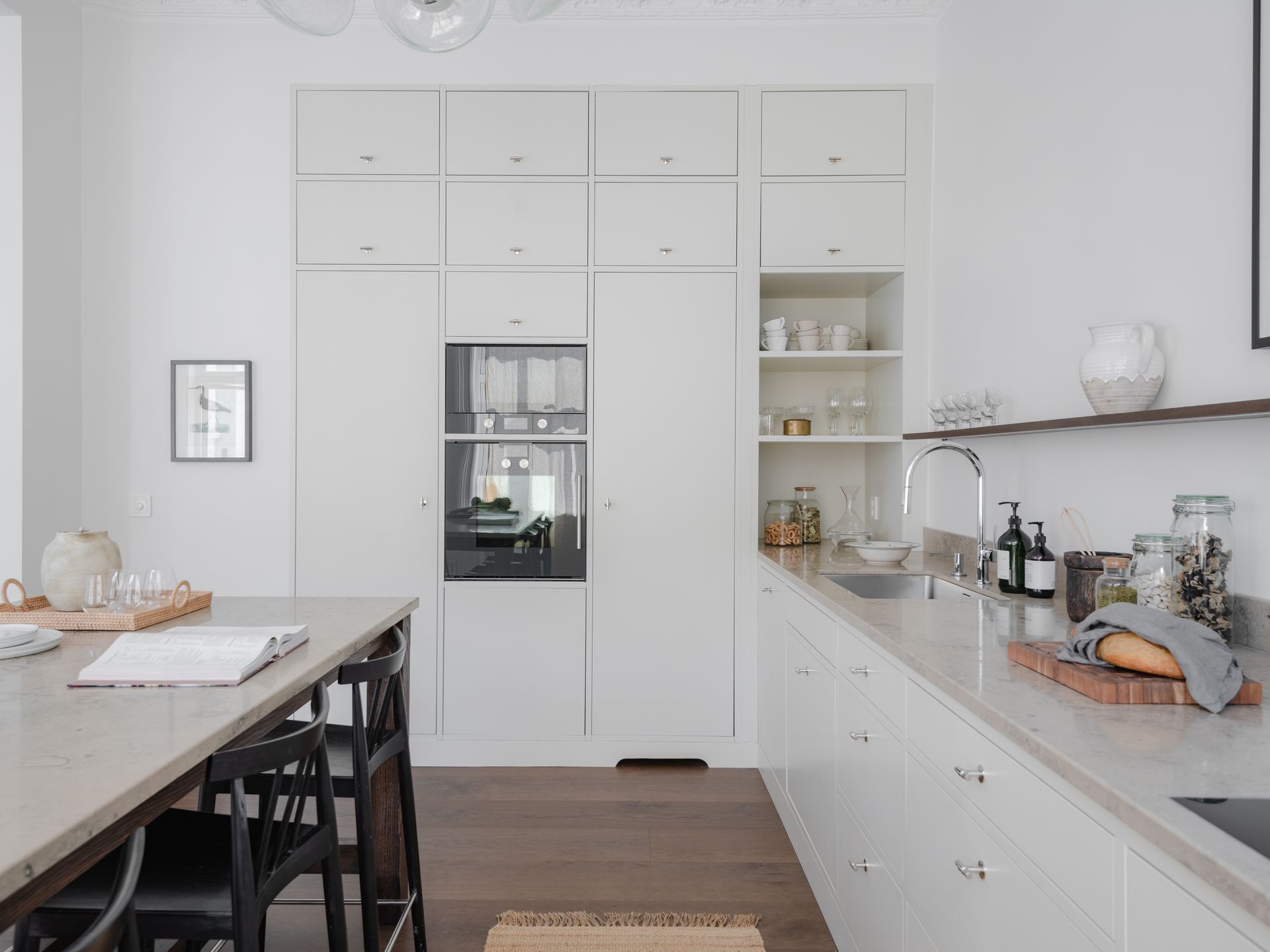 Lyst, moderne kjøkken med hvite skap, kjøkkenøy og hvitevarer på benken