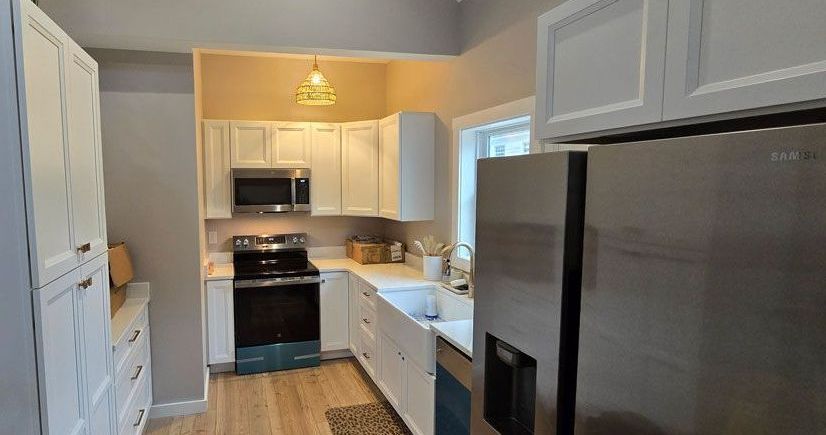 A kitchen with stainless steel appliances and white cabinets.