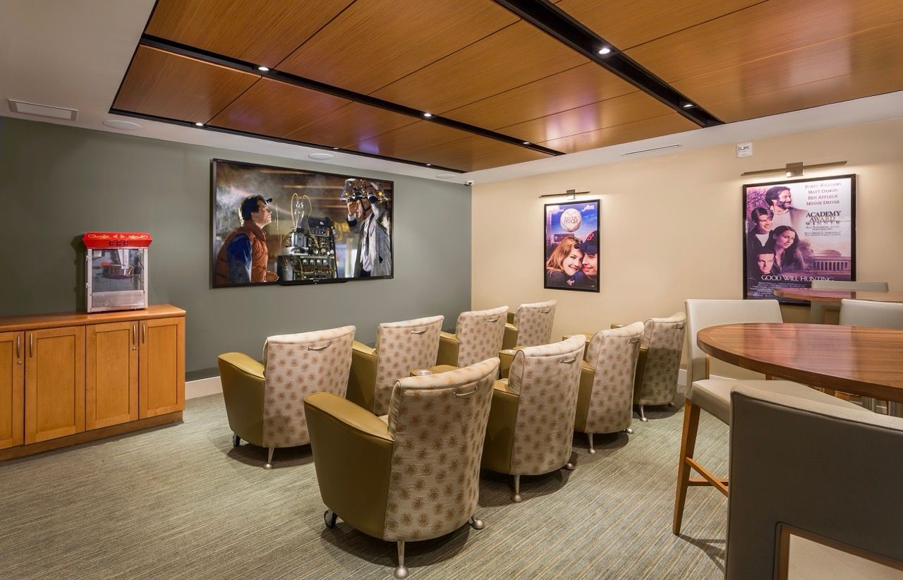 Interior resident lounge with theater-style seating, posters on walls, and a popcorn machine.