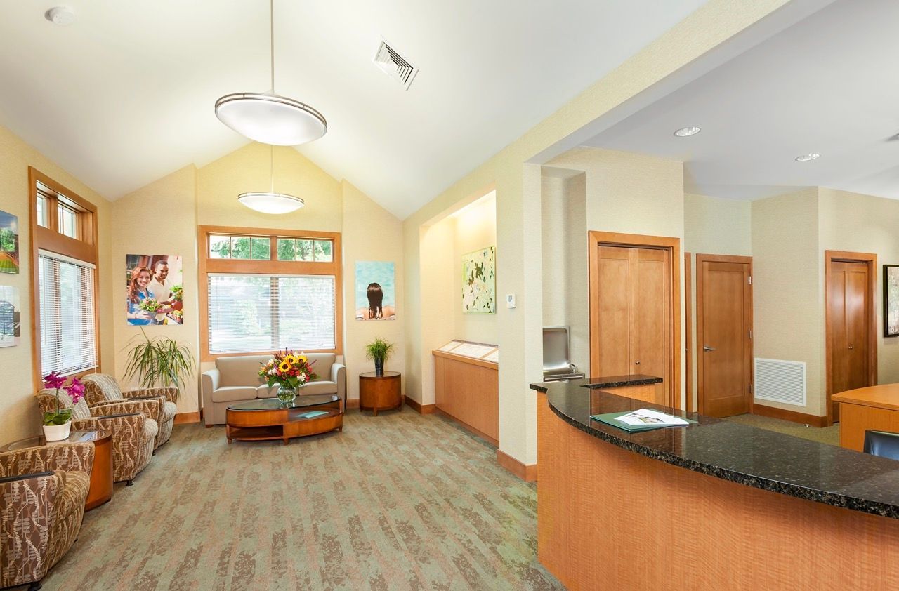 Apartment community lobby with seating area, plants, and a curved reception desk.