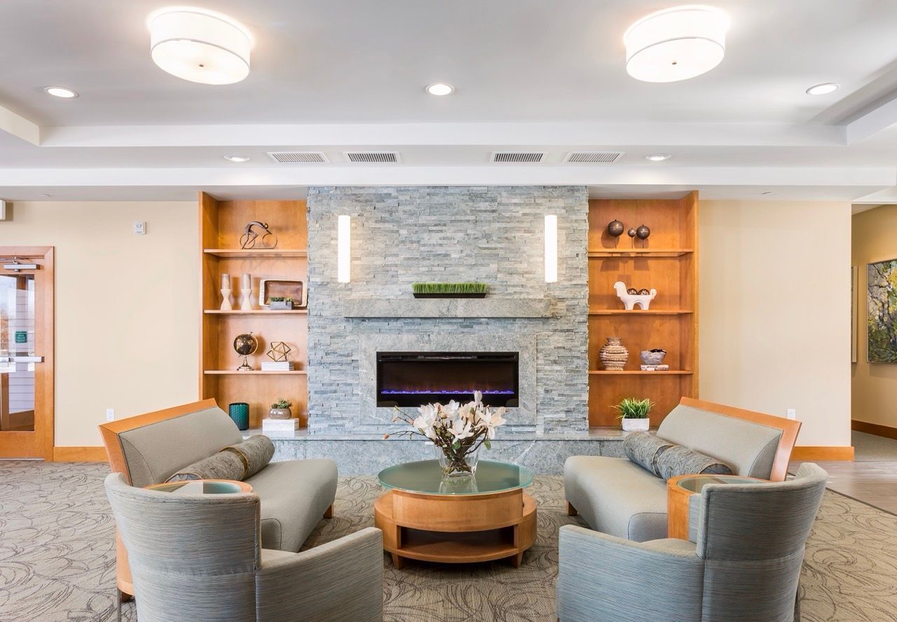 Lobby seating area with a stone fireplace and built-in wooden shelves.