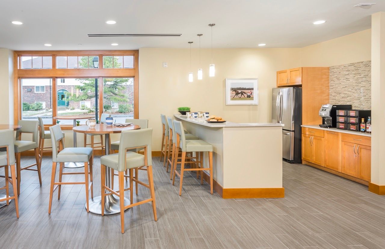 Bright community lounge with a cafe-style bar, seating, and large windows.