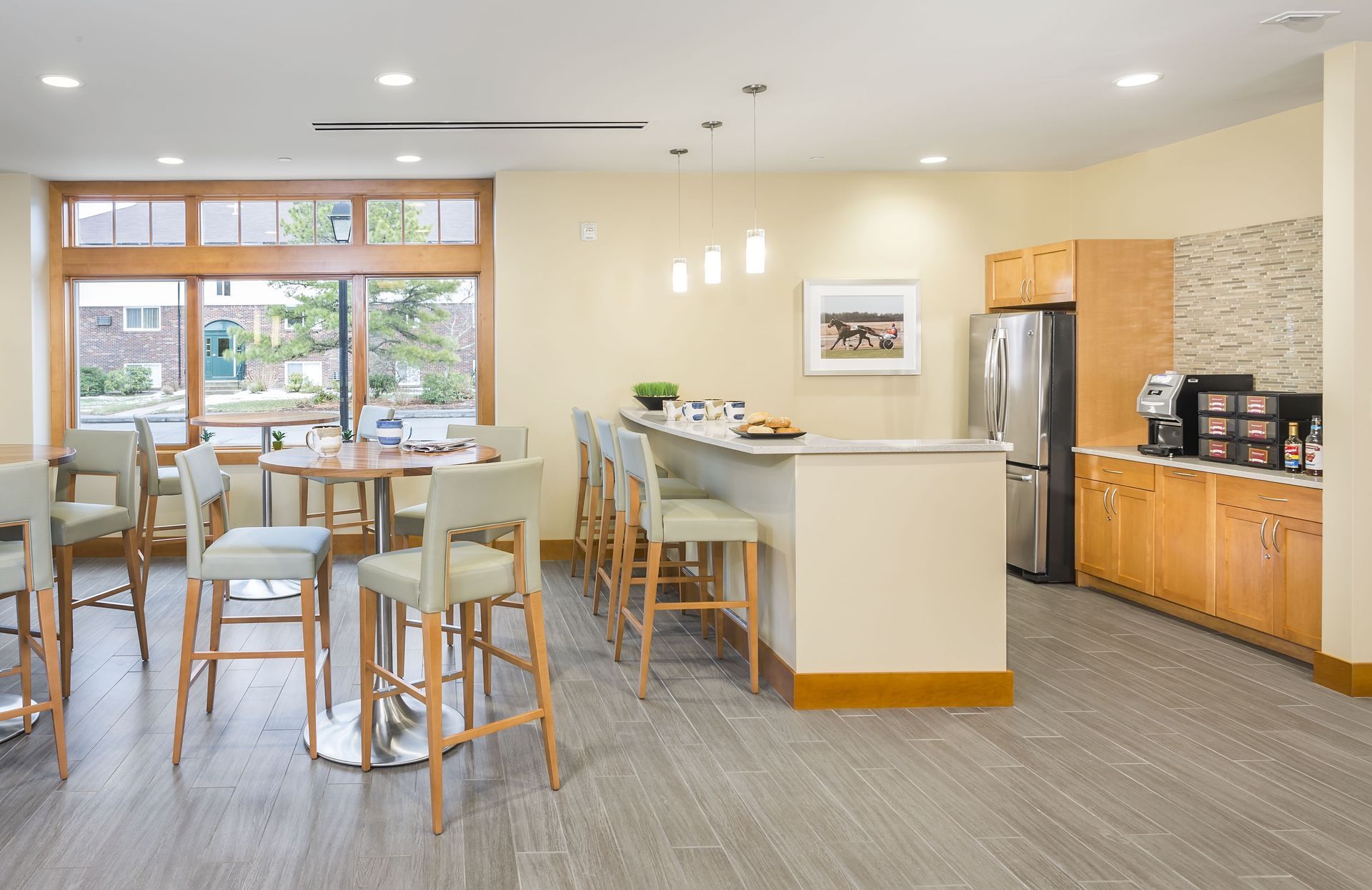 Bright modern kitchen and dining area with island, stools, wood cabinets, and large windows