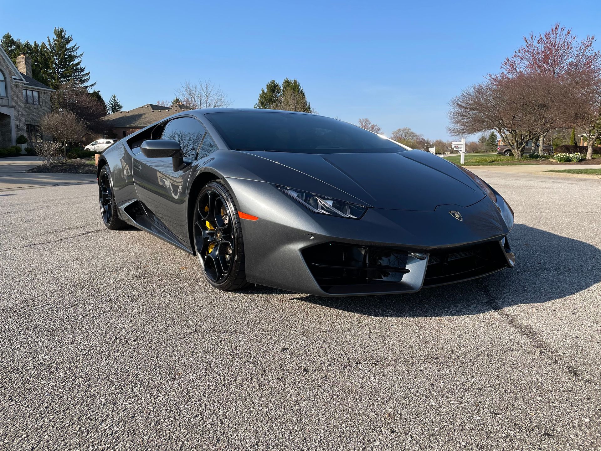 A gray lamborghini huracan is parked in a driveway in front of a house.