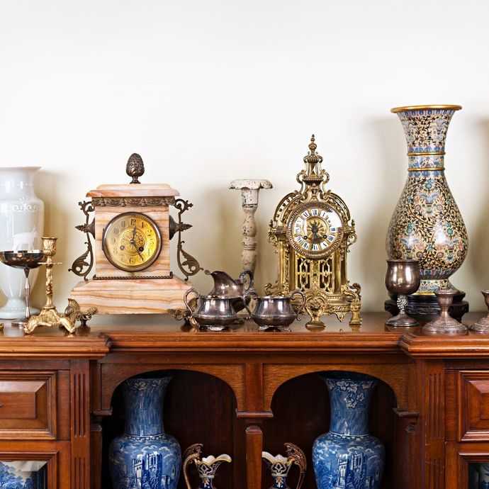 A collection of antique clocks and vases on a wooden shelf