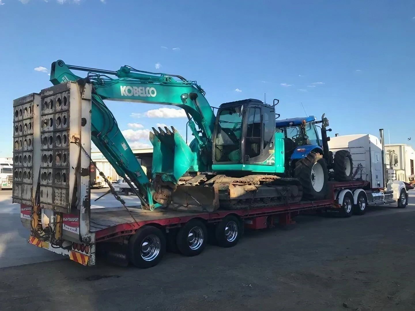 A Kobelco Excavator Is Being Transported on A Flatbed Trailer — Central Coast Complete Demolition & Tree Service in Buff Point, NSW