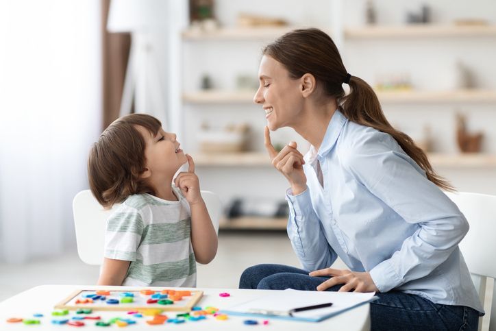 Una donna è seduta a un tavolo e parla con un bambino.
