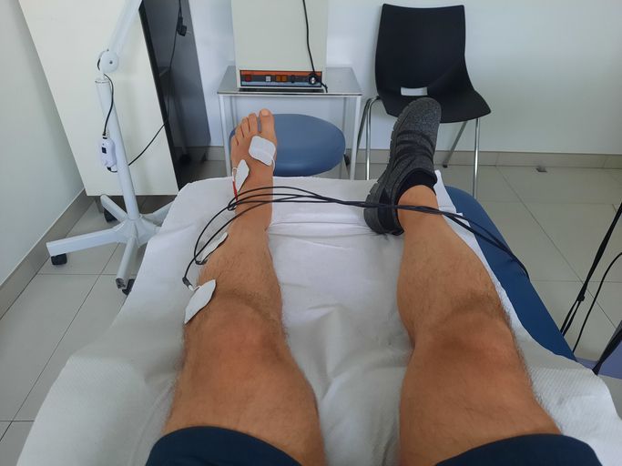 Una persona sdraiata su un letto con fili attorno alle gambe
