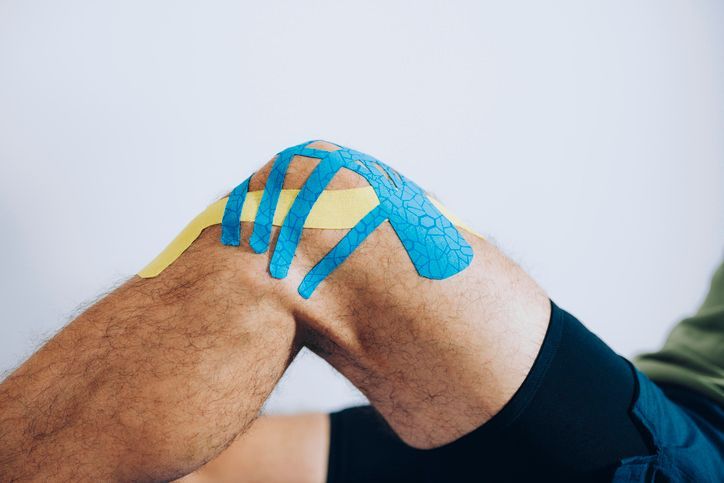 Un primo piano del ginocchio di una persona con del nastro kinesiologico.