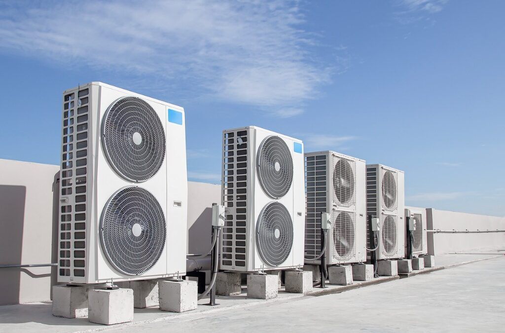 4 exterior commercial air con units on roof with blue sky
