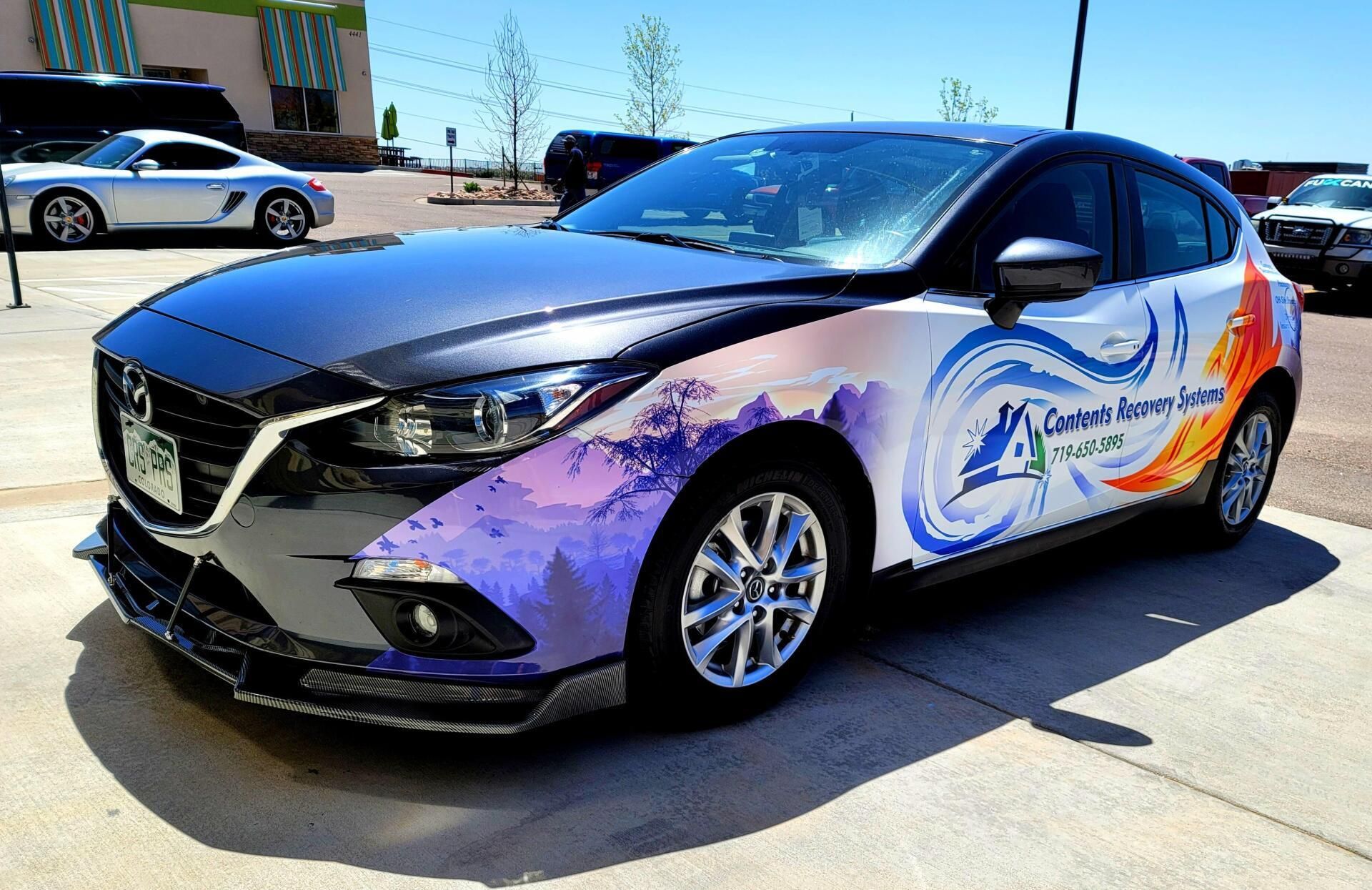 Purple-and-orange branded sedan parked outdoors in bright sunlight