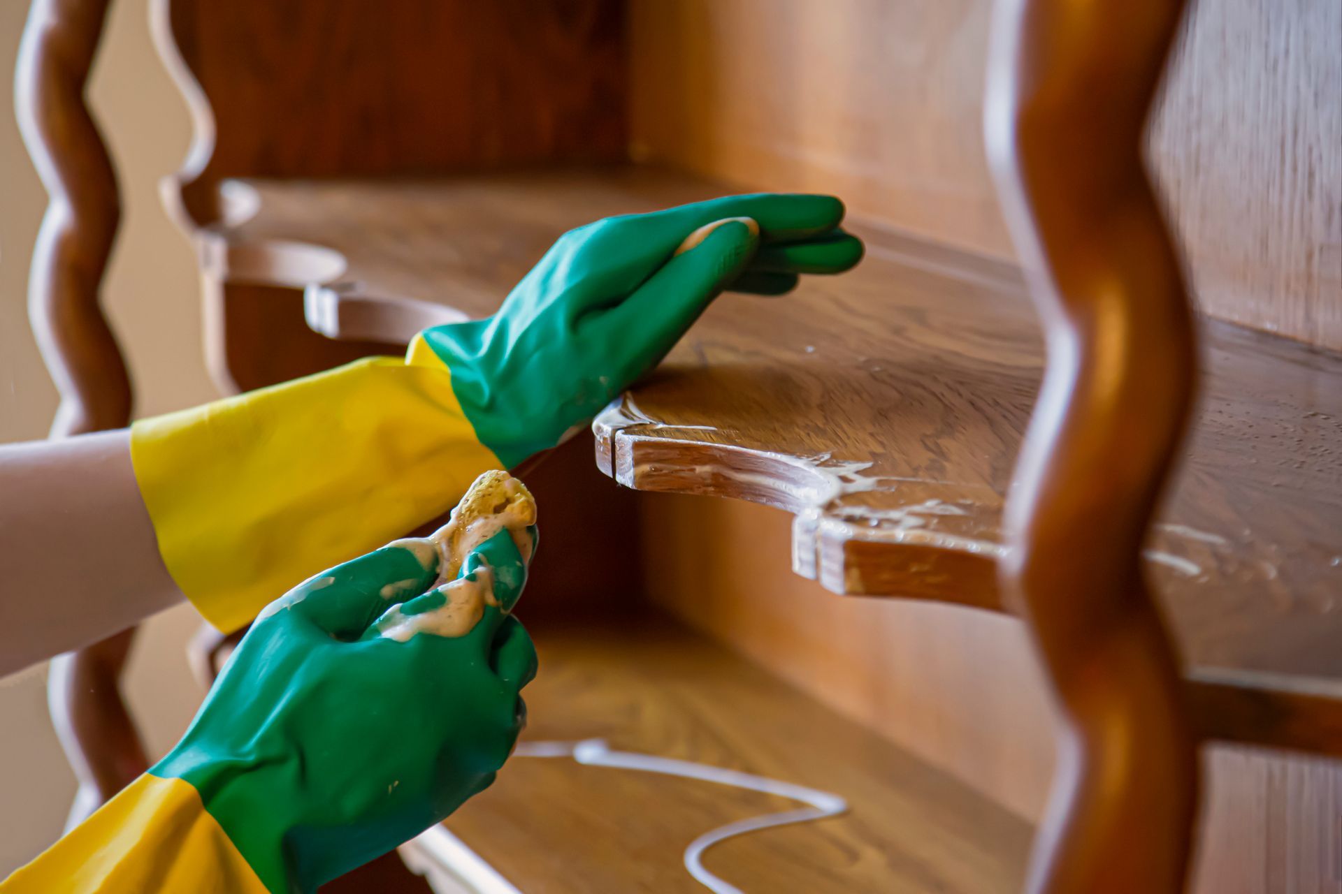 Green-gloved hands polishing a wooden staircase with a cloth