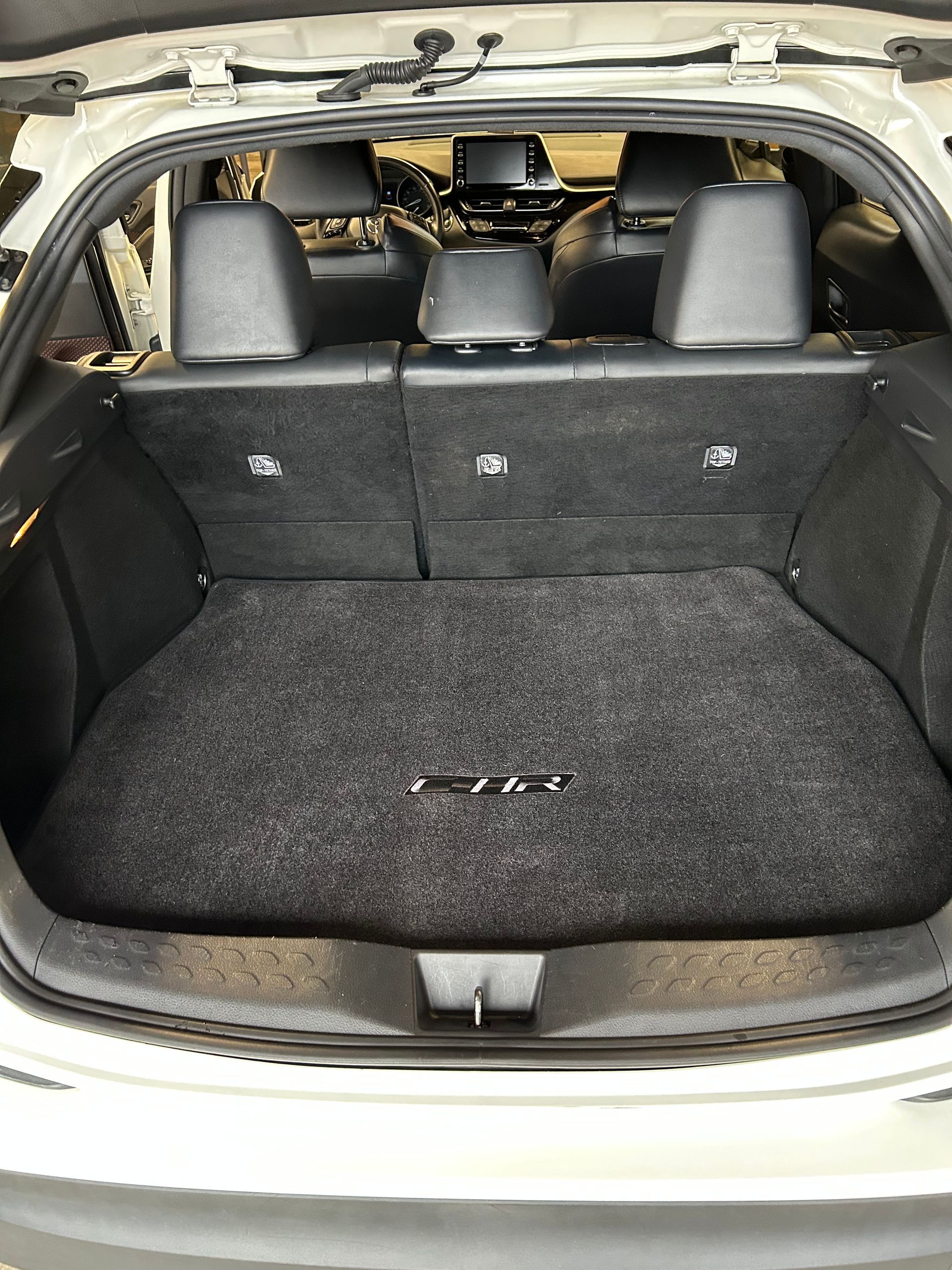 Open car trunk with black carpeted cargo area and rear seats visible through the hatch.