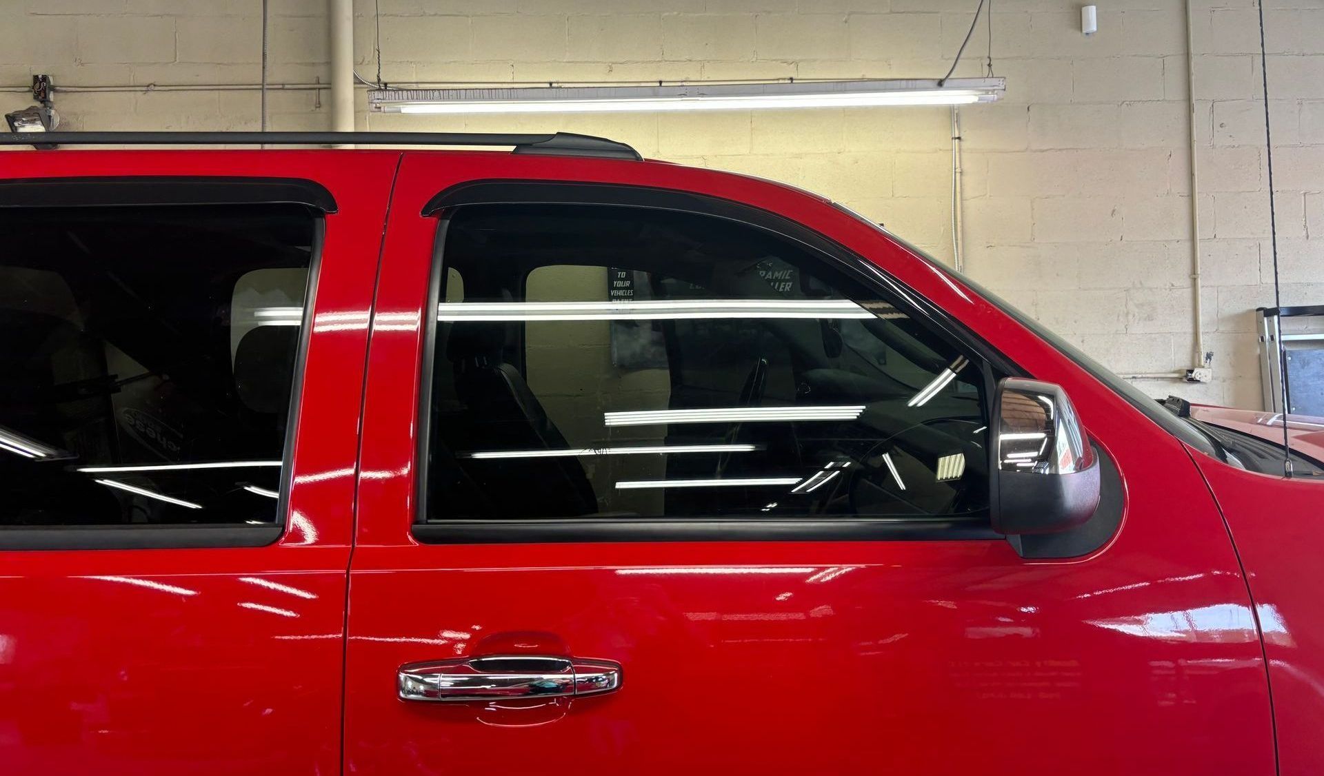 A red van is parked in a garage next to a brick wall.
