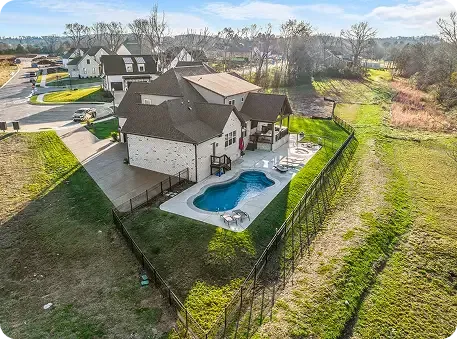Aerial view of a house with a backyard pool, patio, and fenced yard