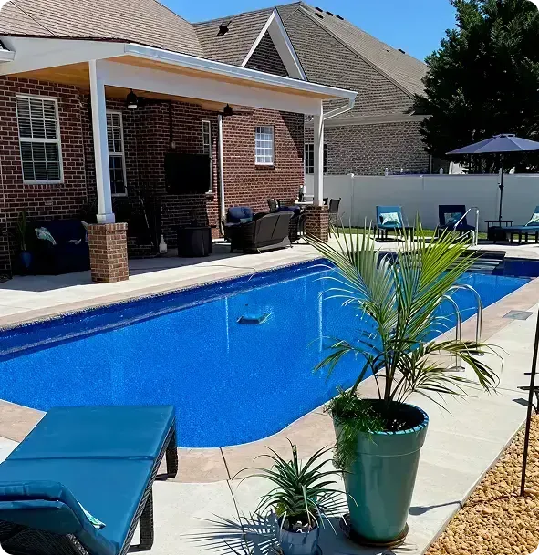 Backyard pool with blue water, patio chairs, potted plants, and a brick house patio.